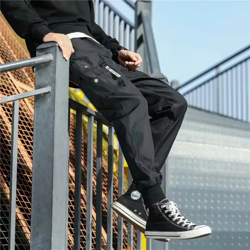 Men tactical cargo pants in black featuring multiple pockets and a white waistband detail designed for durability and utility.