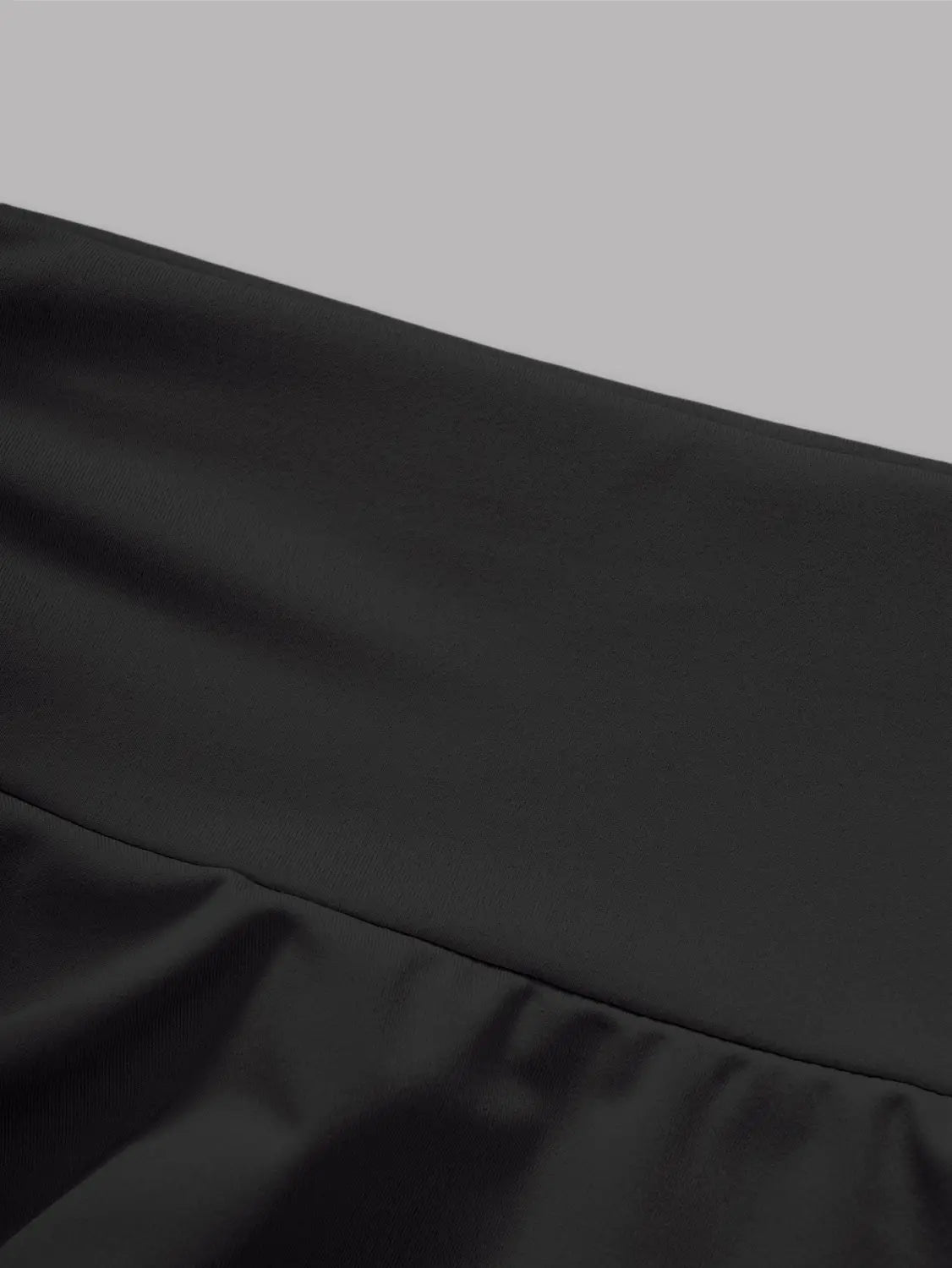 Black high waist ruffle mini skirt made of black satin with a smooth glossy finish and a subtle ruffled hem.