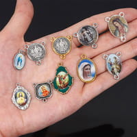 a collection of small ornate metallic religious medallions featuring various saints and icons displayed alongside a saint christopher leather keychain in antique bronze finish