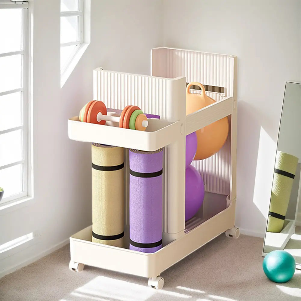 Cream-colored plastic gym equipment organizer trolley with wheels featuring multiple compartments holding yoga mats dumbbells and exercise balls.