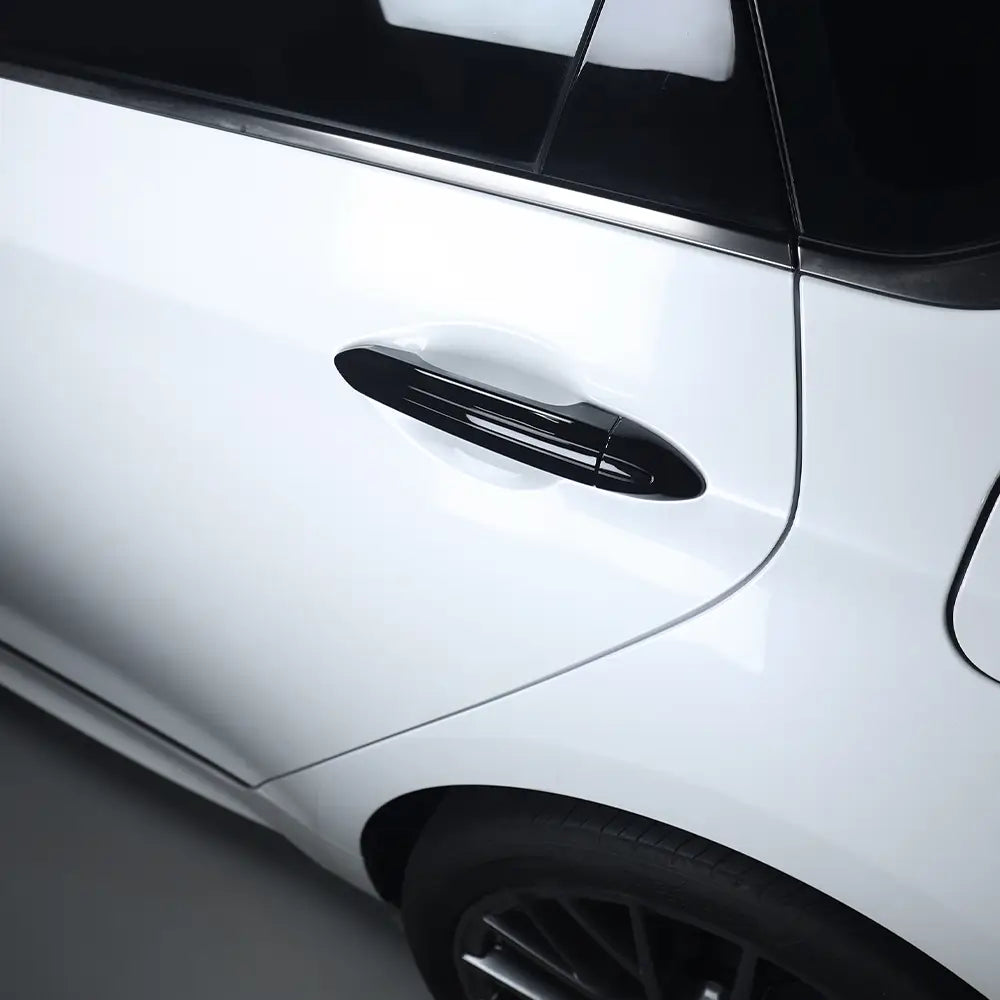 Garniture de protection de poignée de porte en ABS noir brillant, fixée sur une voiture Genesis G80 blanche.