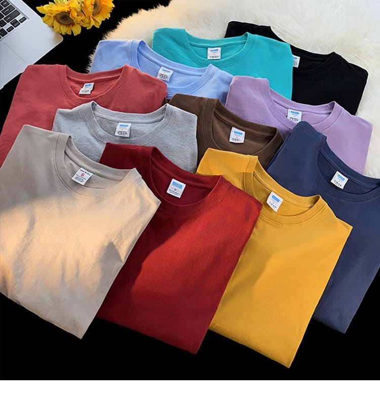 A collection of neatly folded oversized long sleeve blank cotton t-shirts in solid colors including red yellow blue gray and black.