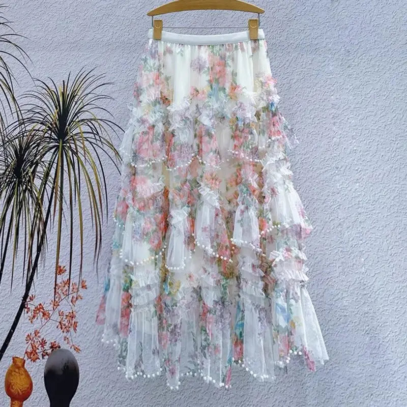 Una falda de tul floral fairycore delicada y de múltiples capas, en tonos suaves pastel de rosa y azul, elaborada con encaje translúcido con capas fruncidas y ribete de perlas.