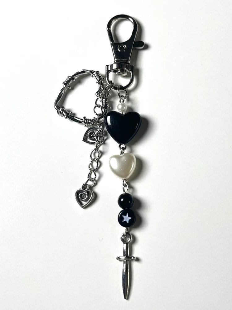 Porte-clés à thème cœur noir et argenté comprenant des pendentifs de barbelés, de perles, de perles-billes et d’épée, mis en avant dans un produit de porte-clés esthétique en forme de cœur noir avec dague.