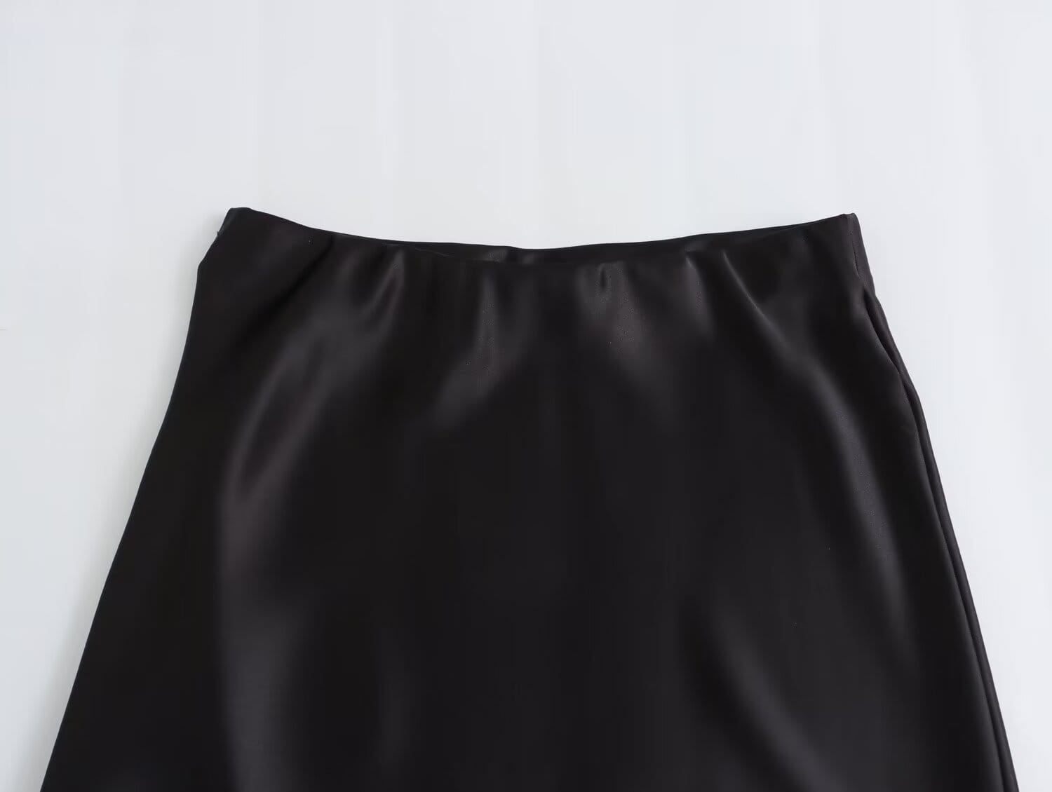 Jupe midi en satin noir à taille haute, finition lisse et brillante, conçue pour un look de longue jupe élégante.