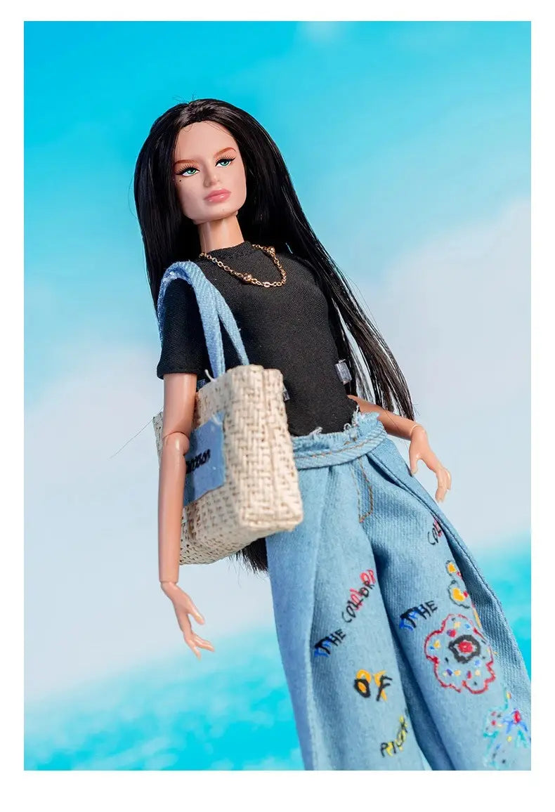 Ensemble de vêtements et d’accessoires de mode pour poupée à l’échelle 1/6, comprenant une poupée Barbie aux longs cheveux noirs portant un haut noir et un pantalon en jean bleu clair avec des écussons brodés de couleurs variées.