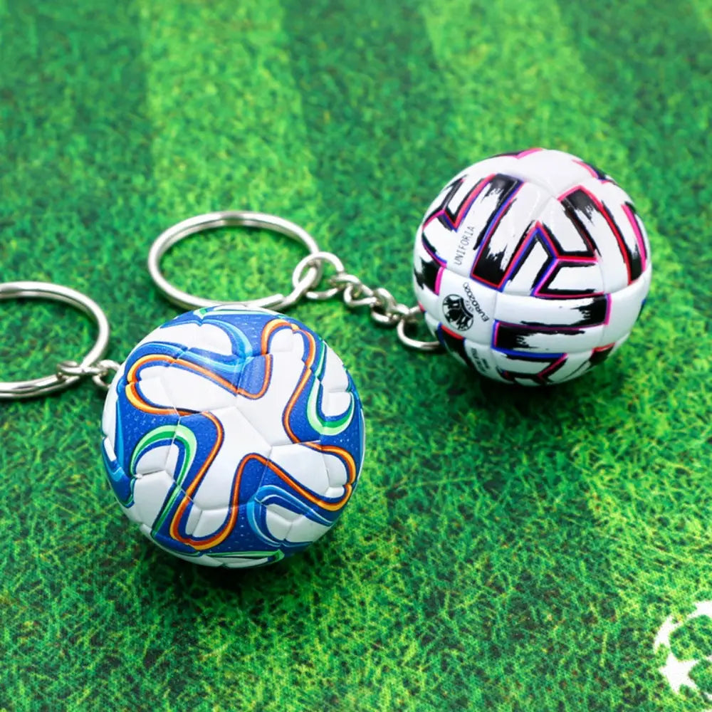 Two leather football keychain sports souvenir pendants featuring miniature soccer balls with one in vibrant blue white orange and green and the other in bold black pink and white.