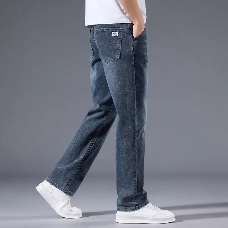 Jeans rétro délavés coupe droite ample pour hommes en denim bleu foncé, avec une décoloration subtile et un petit écusson de logo blanc sur la poche arrière, montrés depuis la face arrière.