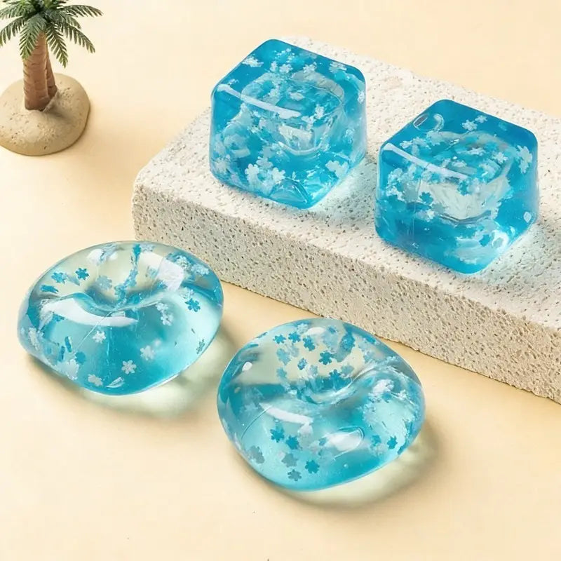 Transparent blue gel ice cubes with embedded white flower patterns designed as slow rising sensory fidget toy ice cubes.