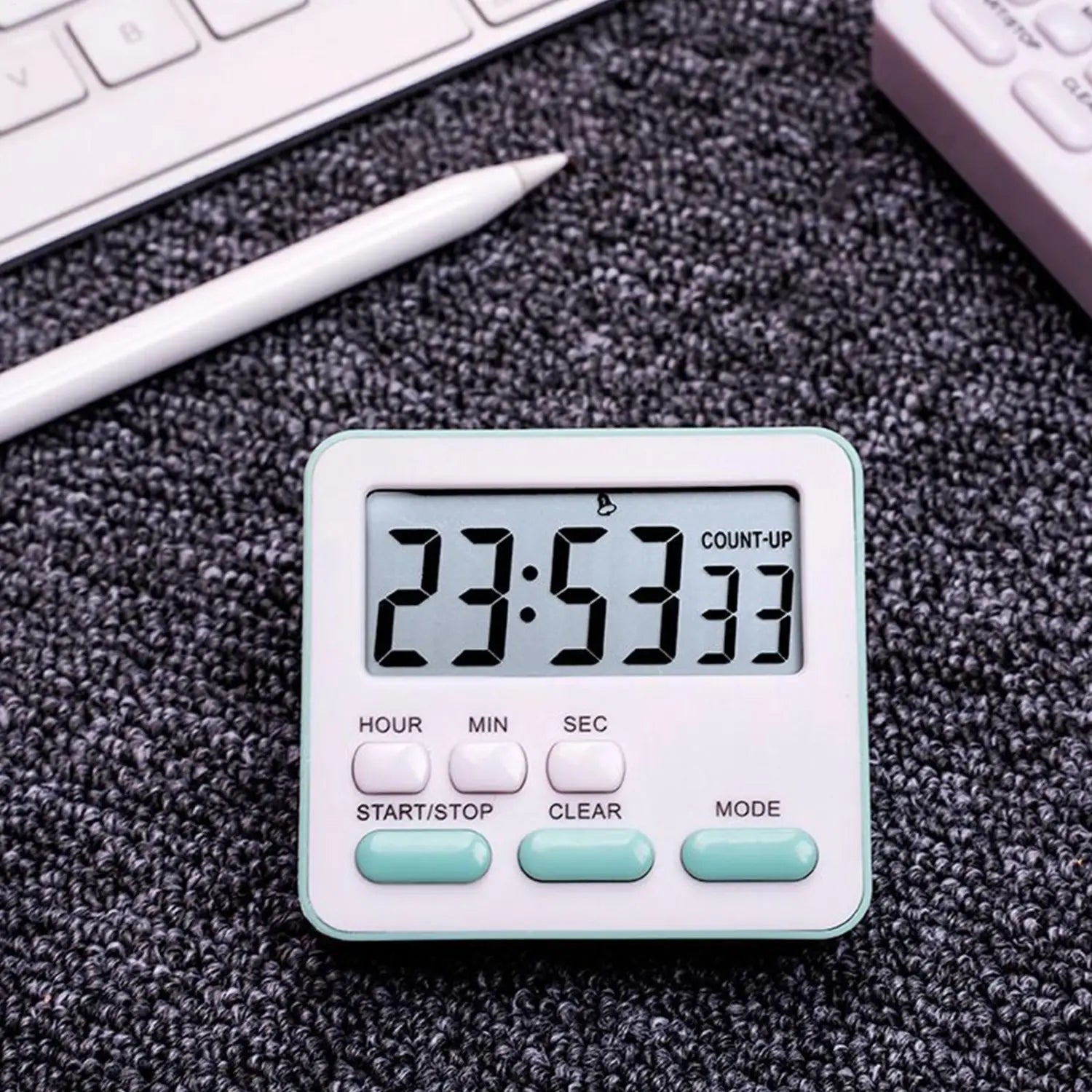 Ein weißer digitaler Küchentimer mit helltürkisen Tasten und einem rechteckigen Display, das 23 53 33 anzeigt, für die Verwendung als geräuschlose Countdown-Uhr.