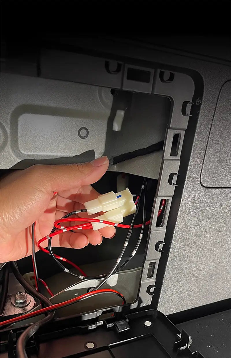 A hand holds red and black wires with white plastic connectors for car trunk lighting fit in the Baic 212 T01 2024 modified auto trunk lighting.