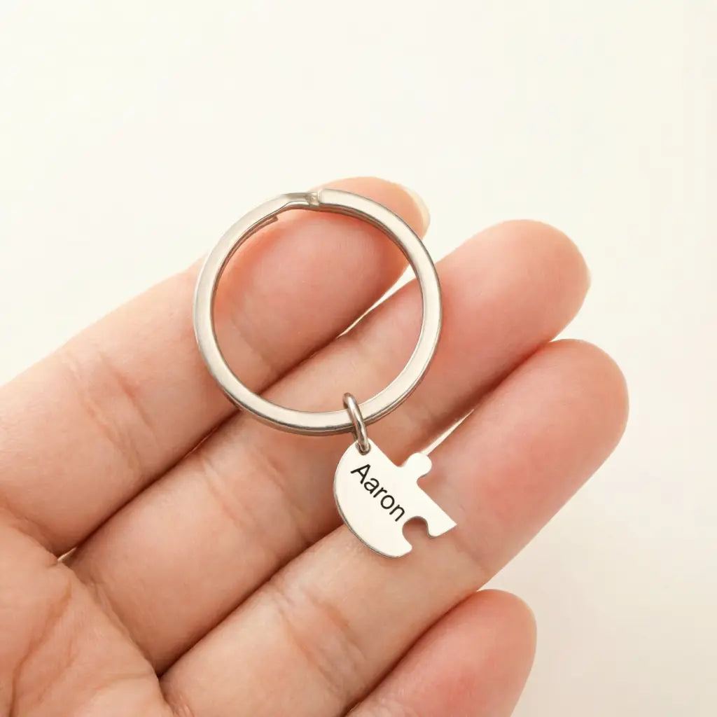 Silver metal puzzle piece keychain engraved with the name aaron from the custom family puzzle heart keychain collection.