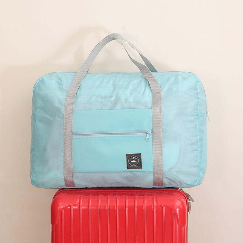 Juego de bolsa de lona de viaje plegable celeste claro con correas grises y un bolsillo frontal con cremallera, diseñado para viajar de forma conveniente.