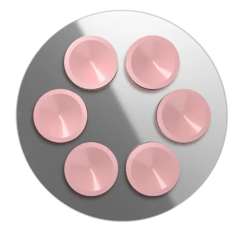 Six capuchons magnétiques à ventouse circulaires roses brillants disposés selon un motif hexagonal sur une surface métallique pour un support de téléphone iPhone Pro Max.