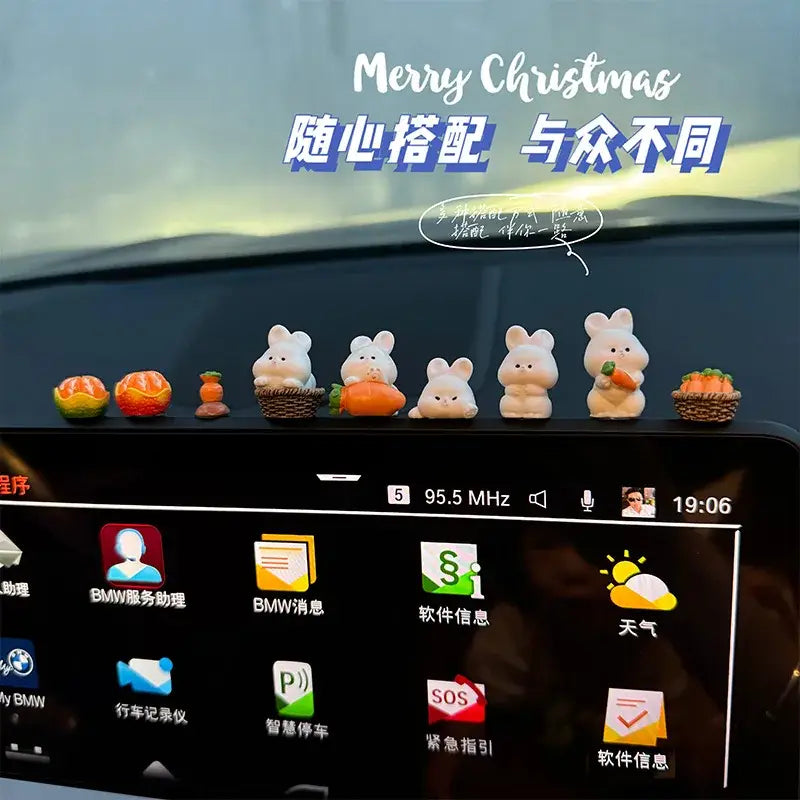 Une rangée d’adorables ornements de tableau de bord de voiture en céramique blanche en forme de lapin, chacun tenant ou assis à côté de mini citrouilles orange et de paniers tressés.