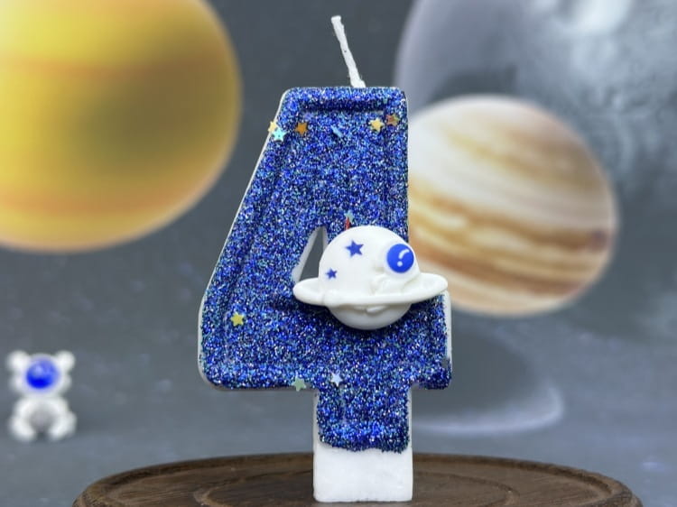 Una vela azul con brillo con el número cuatro para cumpleaños, con una figura de astronauta blanca adherida, diseñada como adorno para pastel de fiesta planetaria para celebraciones temáticas de espacio.