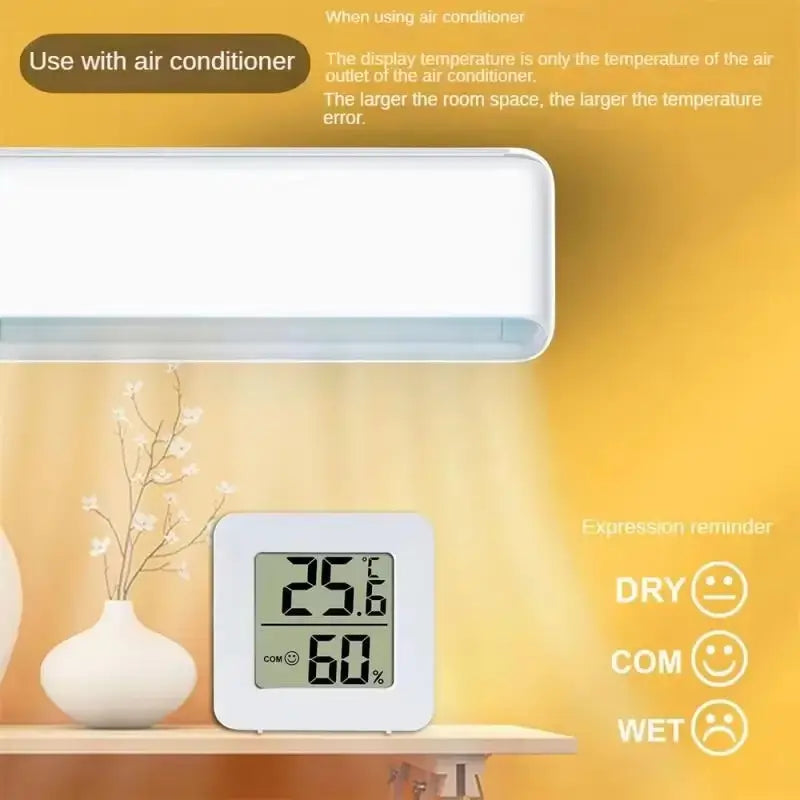 White digital weather desktop alarm clock and hygrometer with a square screen displaying 25.6°c temperature and 60 percent humidity positioned below an air conditioner unit