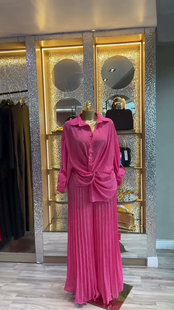Ein lebhaftes pinkfarbenes langärmeliges Hemd mit Knopfverschluss und drapiertem Vordetail, kombiniert mit einem passenden Falten-Maxirock im Damen-Set mit Faltenrockhose im weitem Bein, bestehend aus einem langärmeligen Outfit.