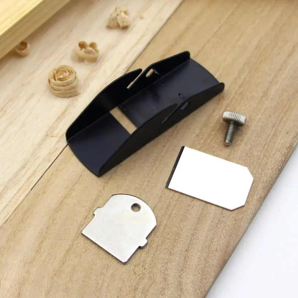 Black mini wood hand planer with aluminum alloy body, metallic blade, and adjustment screw resting on wooden surface alongside replacement parts.