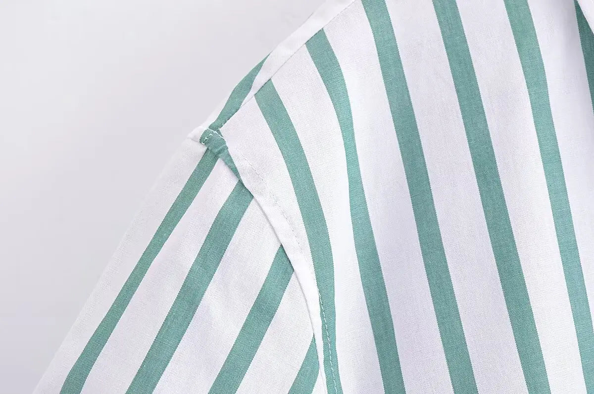 A close-up of the green and white vertically striped fabric with clean stitching on the shoulder seam of a green striped short sleeve crop shirt.