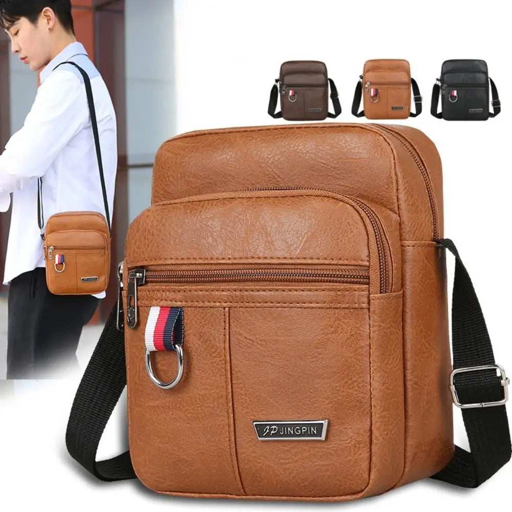 Sac messager bandoulière en faux cuir brun, avec surface texturée, bandoulière de sac messager réglable noire, et une poche zippée avant accentuée par une languette rayée rouge, blanche et bleue conçue comme un sac messager bandoulière traversante pour hommes pour un usage décontracté.