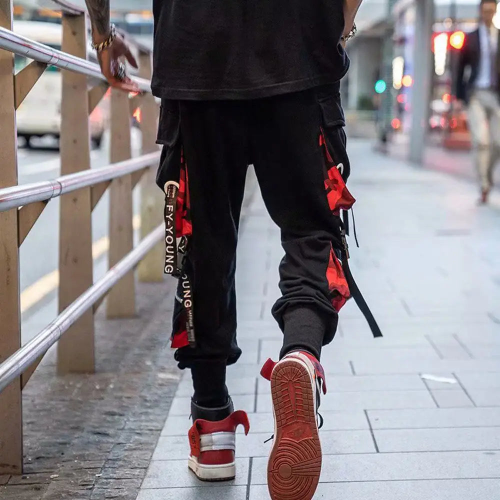 Pantalon cargo joggers streetwear pour hommes en noir, avec des accents de tissu rouge et noir, comprenant plusieurs poches pour un style fonctionnel.