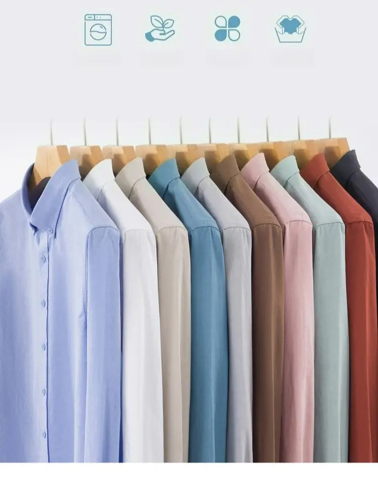 Una fila de camisas Oxford de algodón color azul claro, corte slim fit, para hombre, colgadas de forma ordenada, en tonos pastel suaves y neutros.