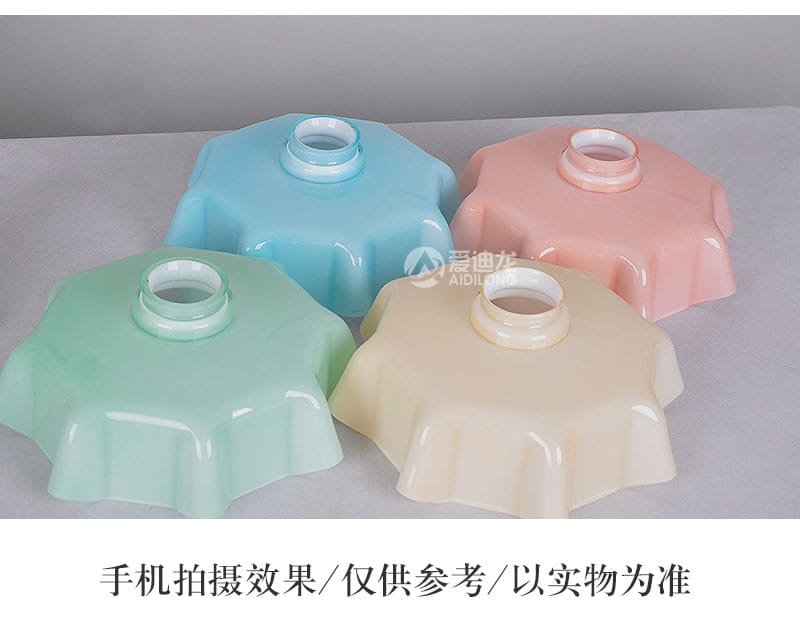 Abat-jours de lampe translucides aux couleurs pastel avec un motif cannelé en forme de pétales et des anneaux de fixation centraux, associés à une tête de lampe en cuivre dans un luminaire suspendu à jupe florale en verre.
