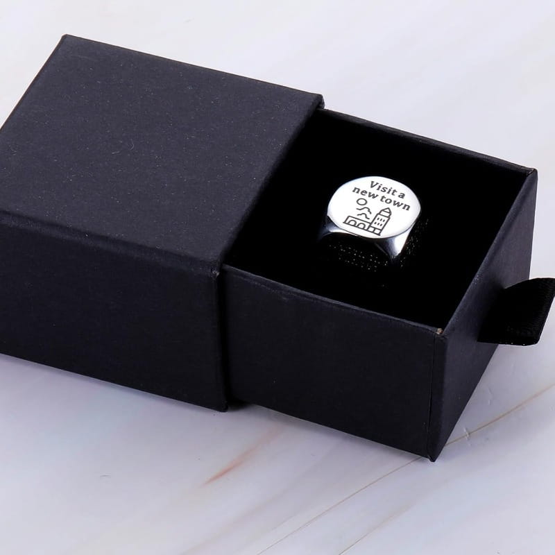 silver stainless steel food decision dice ring with circular face engraved with visit a new town and small tower illustration nestled in black gift box for couples date night