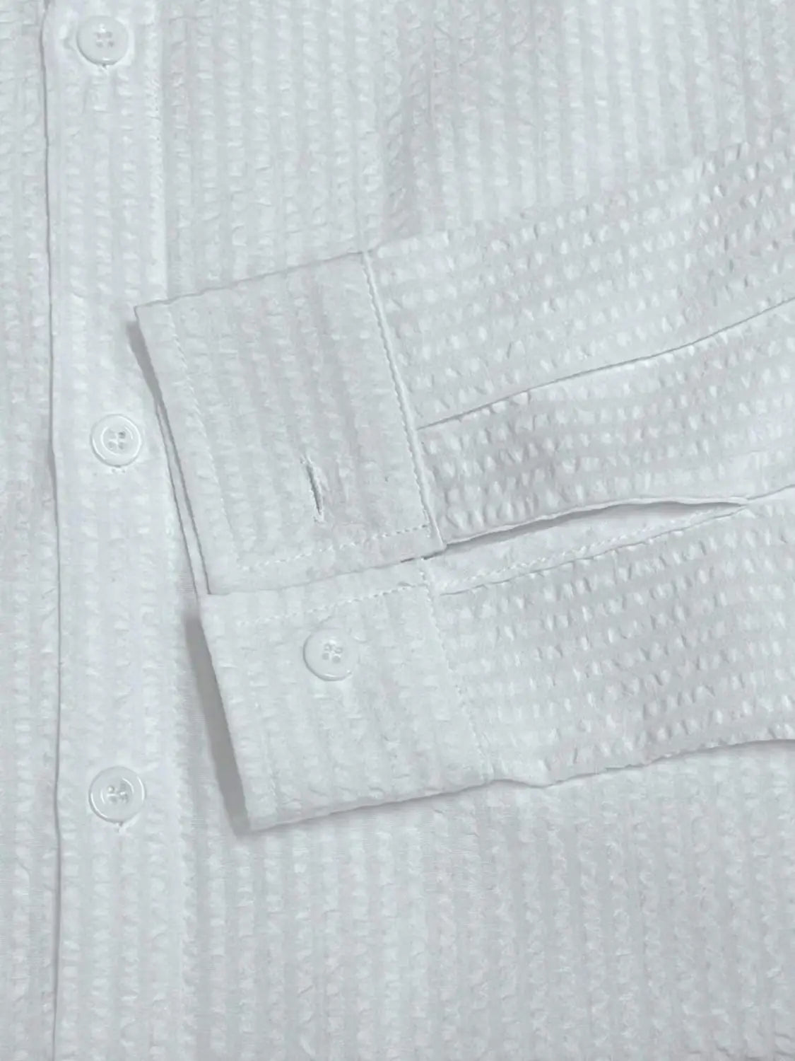 Chemise boutonnée en coton blanc façon gaufré, avec poignets et boutons assortis, conçue comme alternative à une chemise décontractée boutonnée manches longues à rayures bleues pour homme.