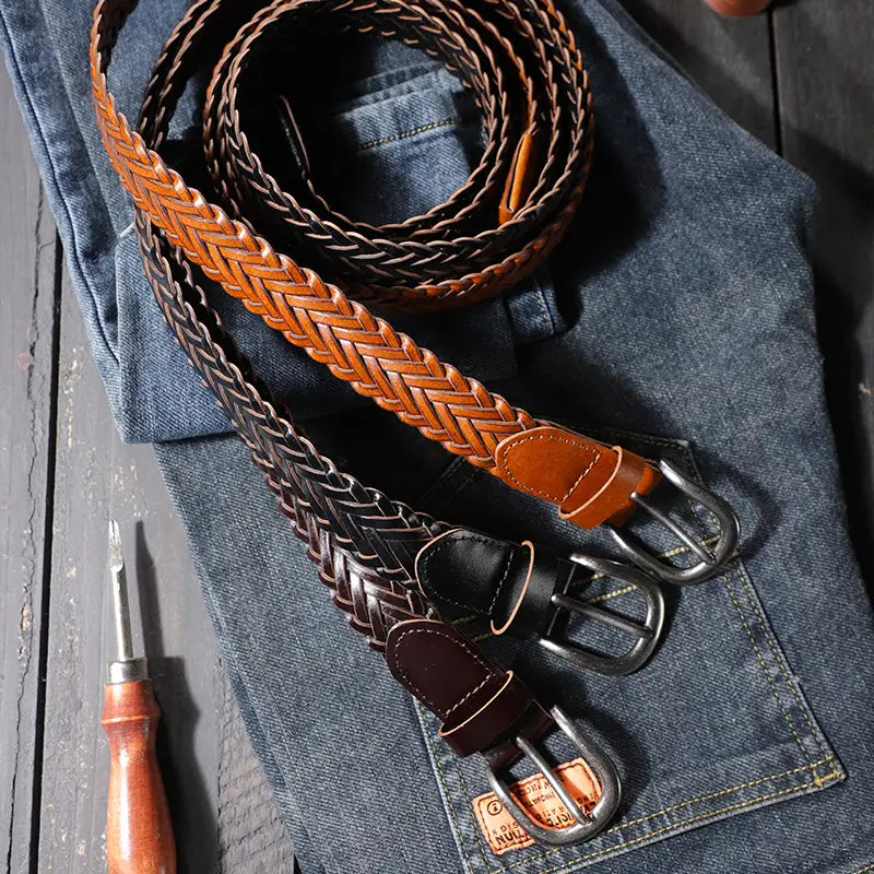 two braided leather belts in tan and black with metal buckles suitable as casual unisex woven accessories