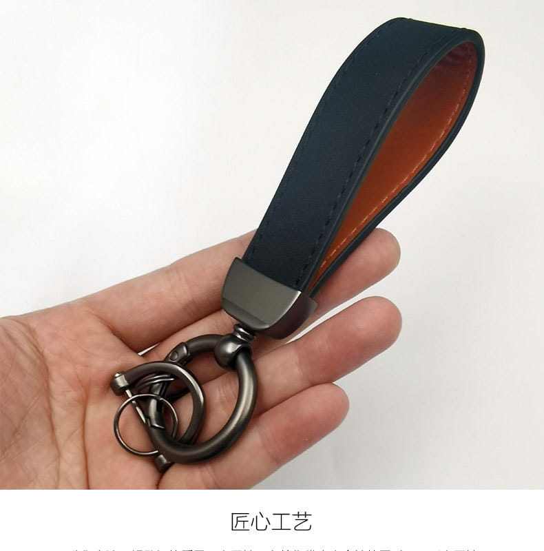 Dark blue genuine leather keychain with contrasting brown interior lining and matte black metal ring for car key use.
