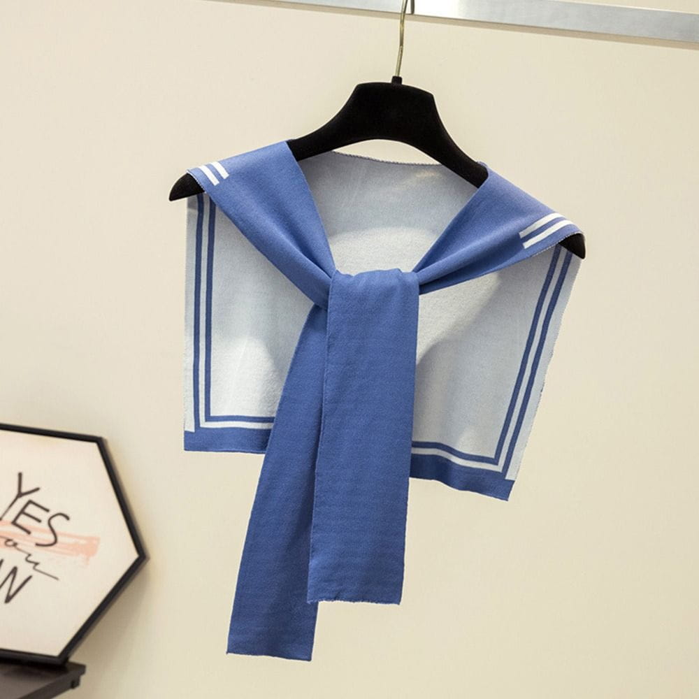 Blaues gestricktes Matrosen-Style Cropped-Top mit weißem Besatz und drei Streifen auf jeder Schulter, an einem schwarzen Kleiderbügel hängend, als Teil eines Produkts aus gestricktem Schal mit Fake-Kragen im Matrosenstil.