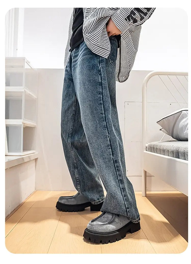 Baskets décontractées à plateforme en suède à semelle épaisse pour hommes associées à un jean à jambes larges en denim bleu délavé, avec coutures visibles et une silhouette droite ample et décontractée.