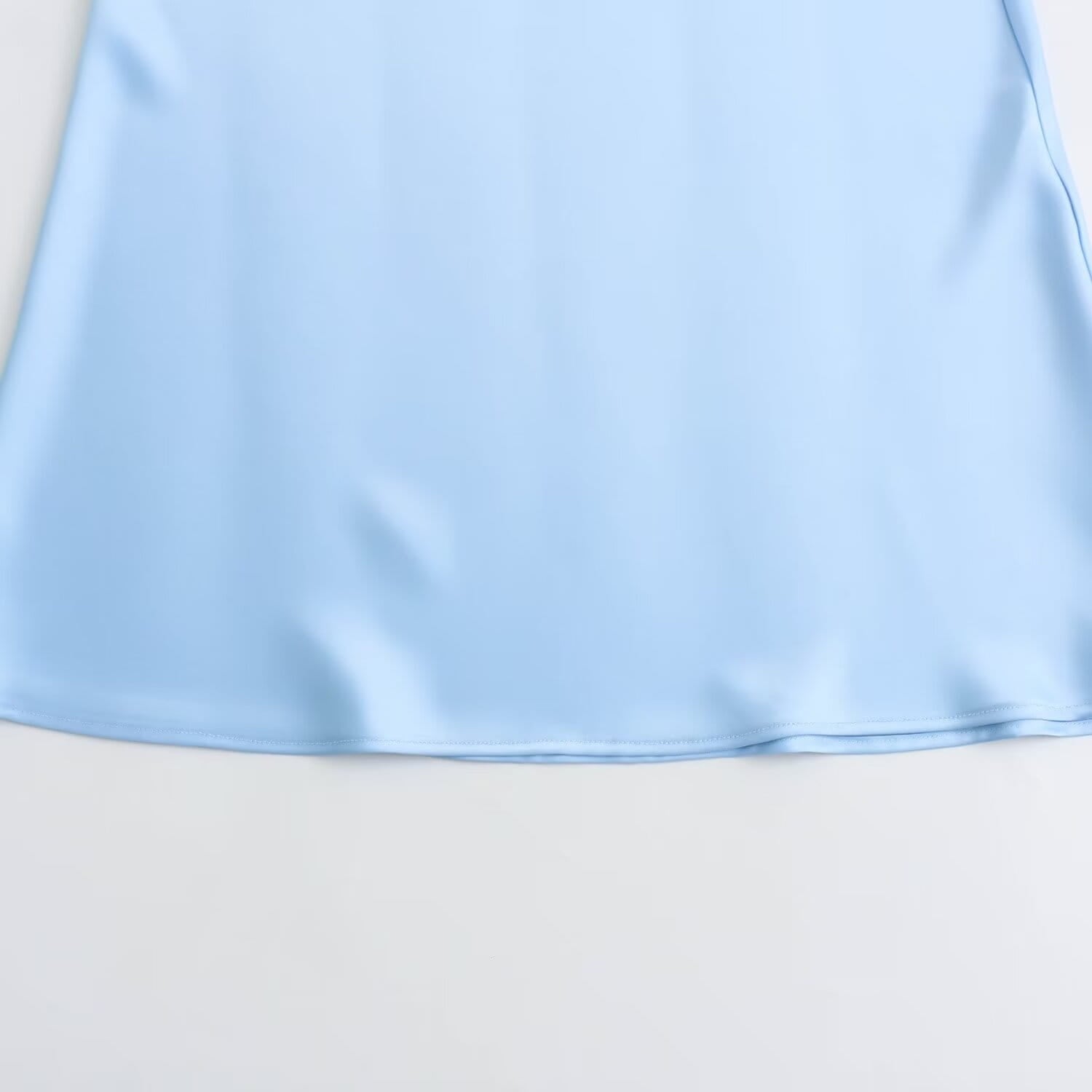 Une jupe midi en satin bleu clair tendre, à taille haute, avec un tissu fluide et une légère brillance pour une allure élégante.