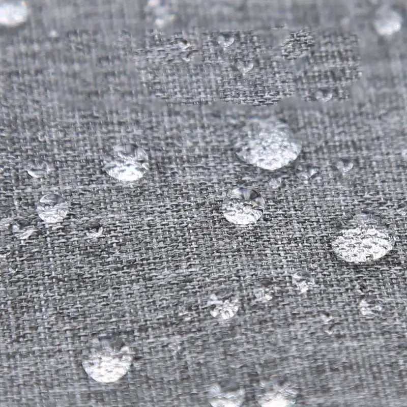 Graues gewebtes Material des universellen Kinderwagen-Sonnenschutzes UPF50 mit Wassertröpfchen, die sich auf seiner Oberfläche sammeln, als Nachweis für Wasserbeständigkeit.