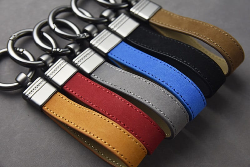 Set of five leather keychains in tan red gray blue and black with silver-toned metal clasp for secure attachment.