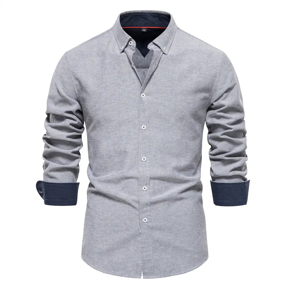 A men’s gray dress shirt with navy blue contrast trim on the collar, cuffs, and inner lining designed as a long sleeve fashion social shirt.