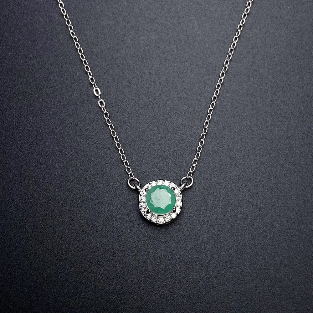 A delicate sterling silver chain necklace featuring a central round emerald surrounded by a halo of sparkling diamonds from the emerald sterling silver jewelry set.