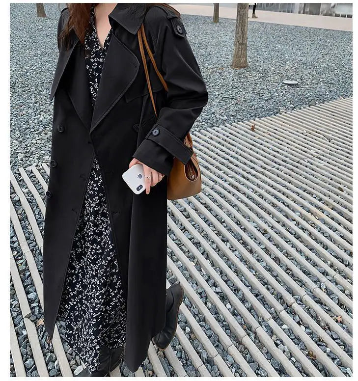 Black women’s double breasted trench coat featuring a classic design with buttoned cuffs.