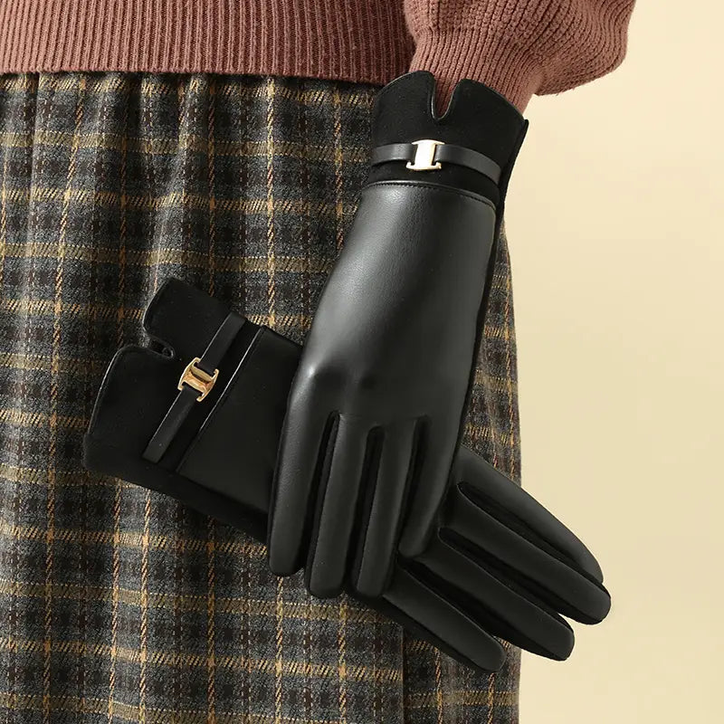 Schwarze Damen-Winterhandschuhe aus Leder mit Touchscreen-Funktion, mit schlankem, glänzendem Finish und goldfarbenen Schnallenakzenten am Handgelenk, von der Rückseite betrachtet.