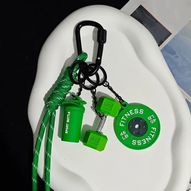 Green fitness keychain with a carabiner, braided cord, and miniature shaker bottle, dumbbell, and plate accessories as a colorful gym bag charm.