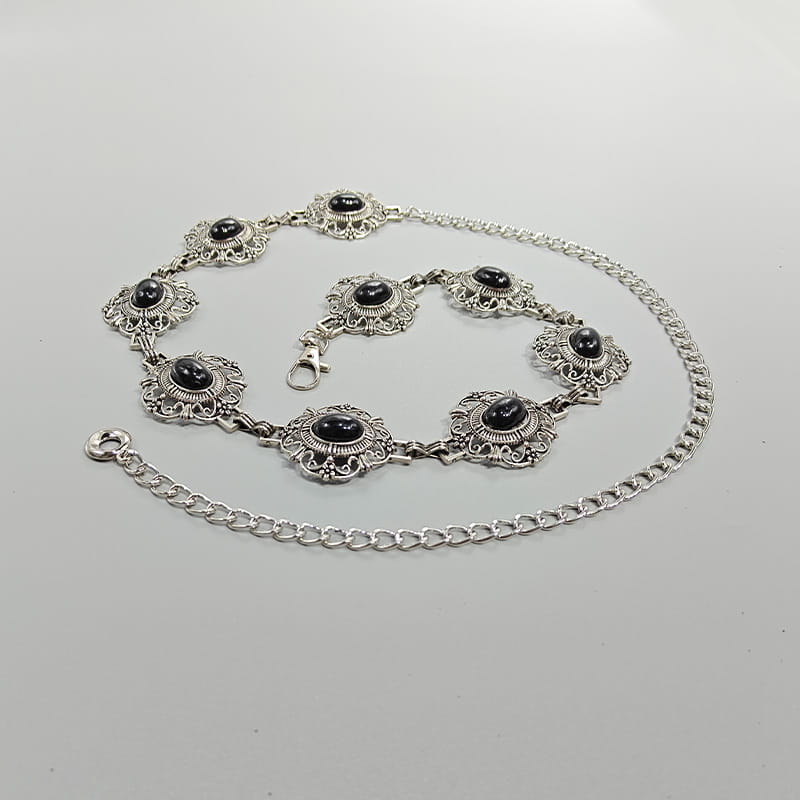 Ceinture de hanche en chaîne argentée, avec des maillons floraux ornés et des pierres d’onyx noir centrales, conçue comme ceinture de hanche pour cosplay pour une femme, style gothique punk