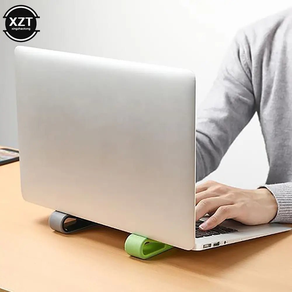 Portátil plateado apoyado sobre una base de enfriador ergonómico ajustable verde y gris, diseñado para mejorar la postura y la ventilación.