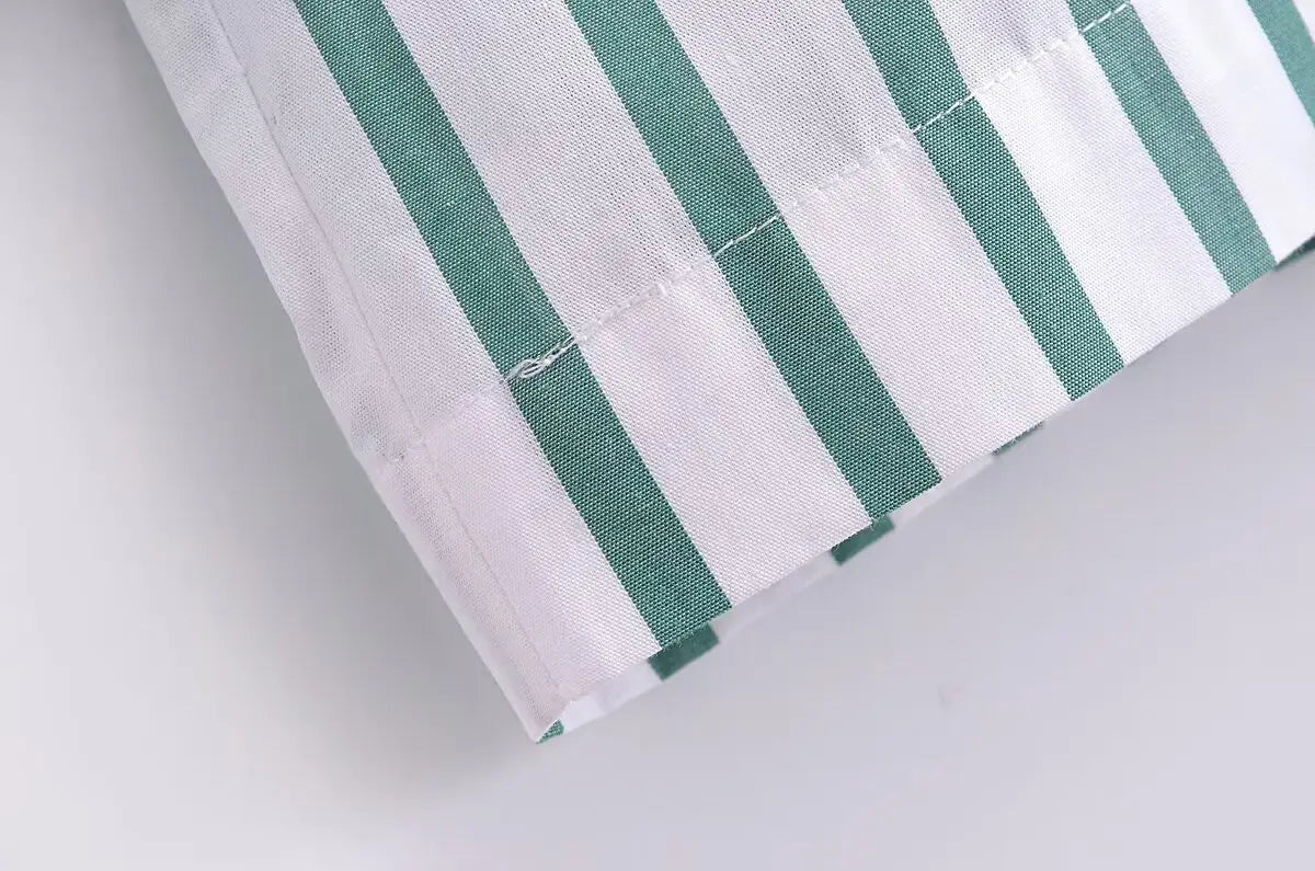 A close-up of fabric with vertical green and white stripes and neat stitching along the folded edge on a green striped short sleeve crop shirt.