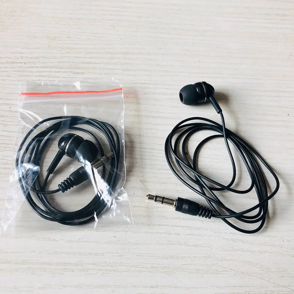Écouteurs filaires noirs avec connexion filaire 3,5 mm et embouts flexibles en silicone, soigneusement enroulés à côté d’un emballage en plastique transparent pour un usage avec mp3 mp4.