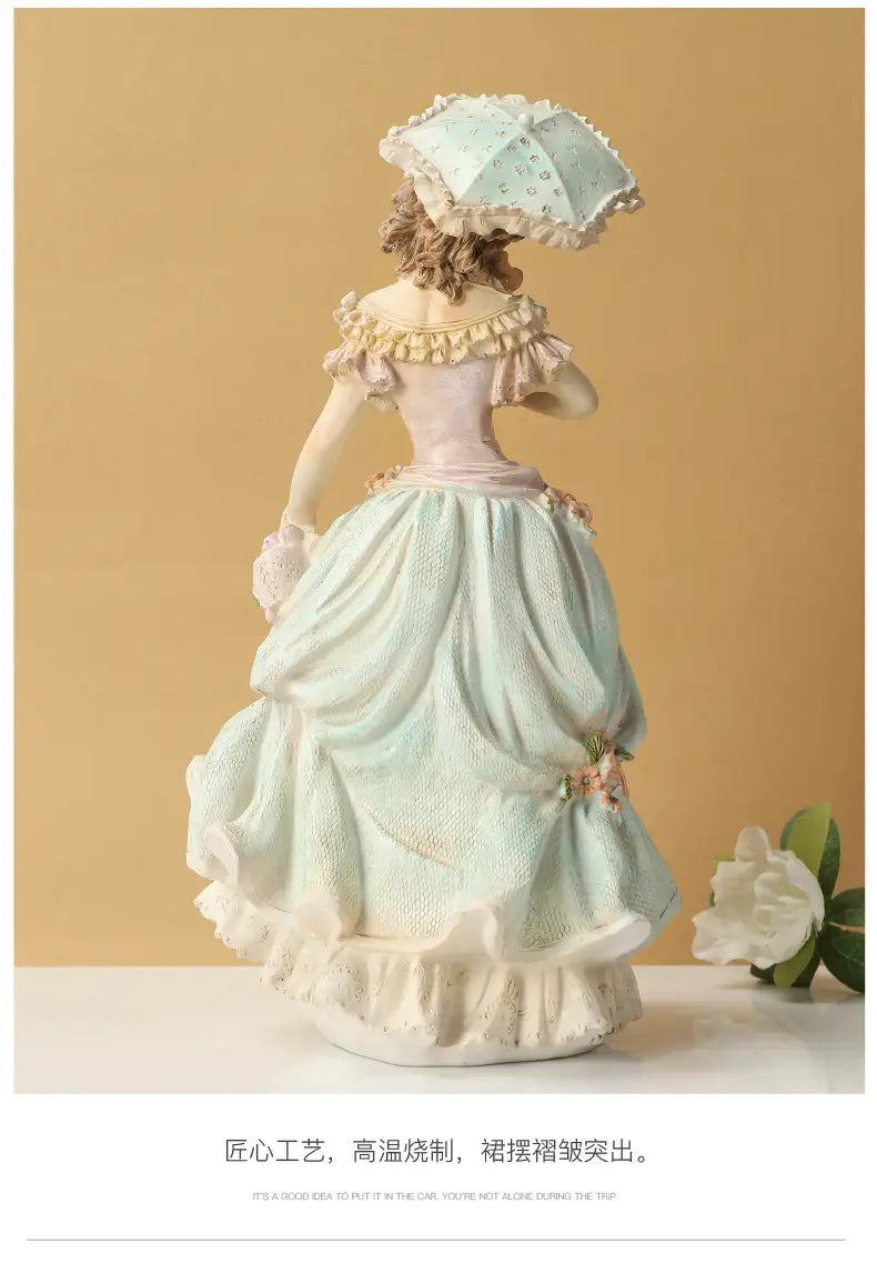 A delicate porcelain Victorian couple resin figurine home decor of a woman in an elegant light blue and white gown with ruffled sleeves holding a matching parasol.