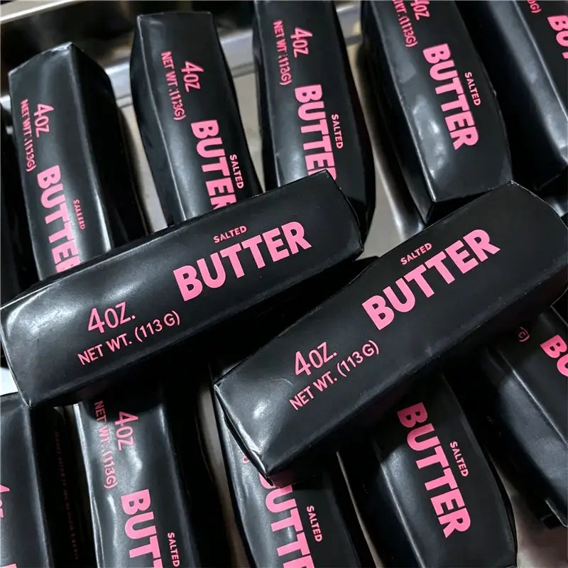 Schwarze verpackte gesalzene Buttersticks mit pinkfarbener Beschriftung, gestaltet als Butterstick-ASMR-Sensory-Squishy-Spielzeug.