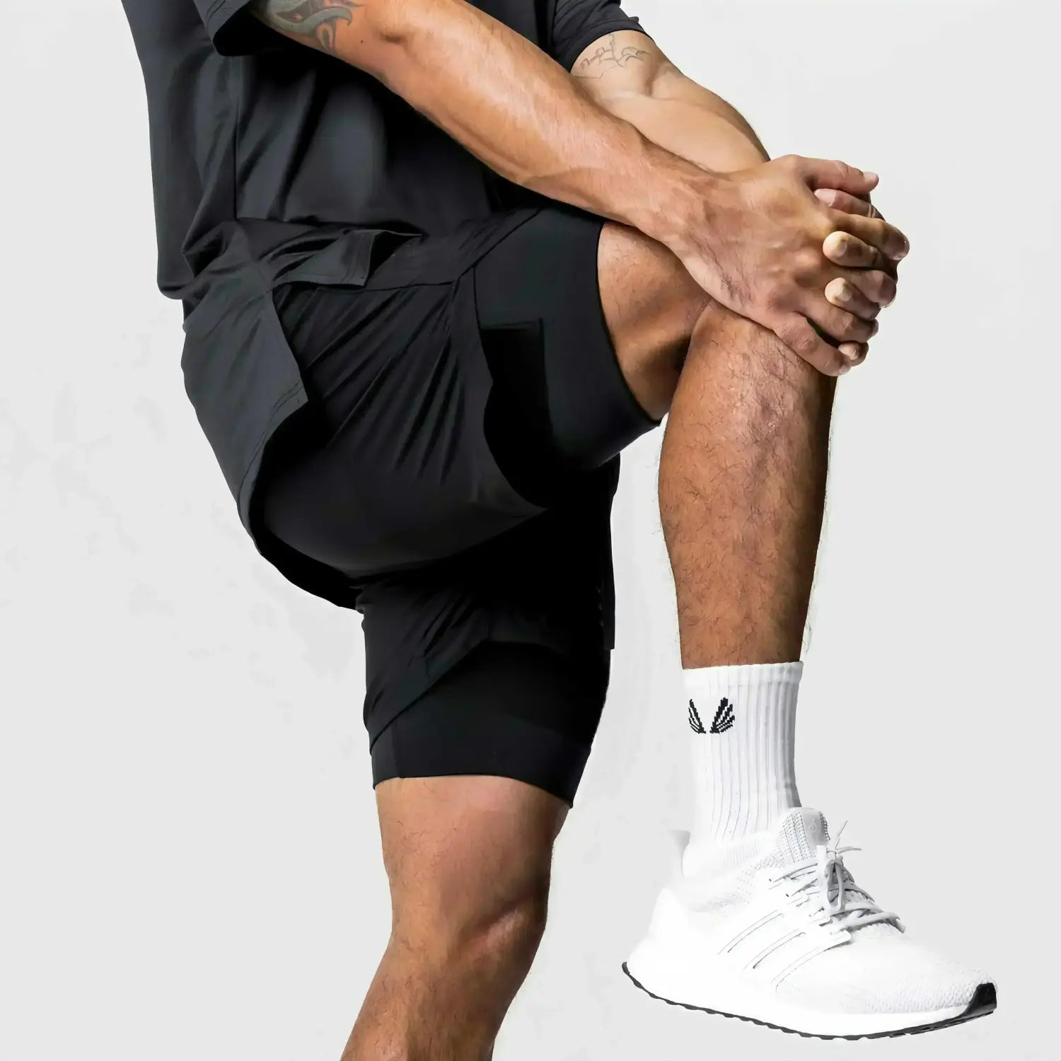 Zapatilla de running adidas ultraboost blanca con suela y cordones negros, combinada con pantalones cortos de entrenamiento para anime de gimnasio 2 en 1 para hombres que incluyen una trabilla para la toalla que ofrece soporte durante el ejercicio.