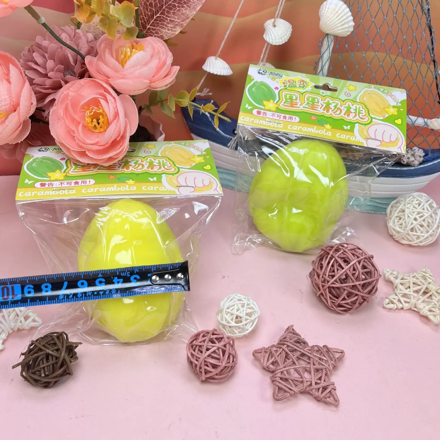 Juguete blando de fruta estrella que cambia de temperatura con acabado brillante de color amarillo verdoso, con forma de carambola, envasado en plástico transparente con etiqueta verde y blanca.